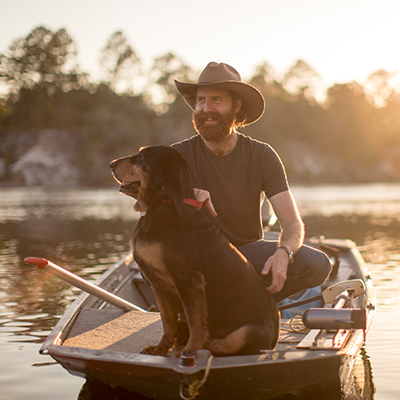 Sean Dietrich paddling his boat with his dog